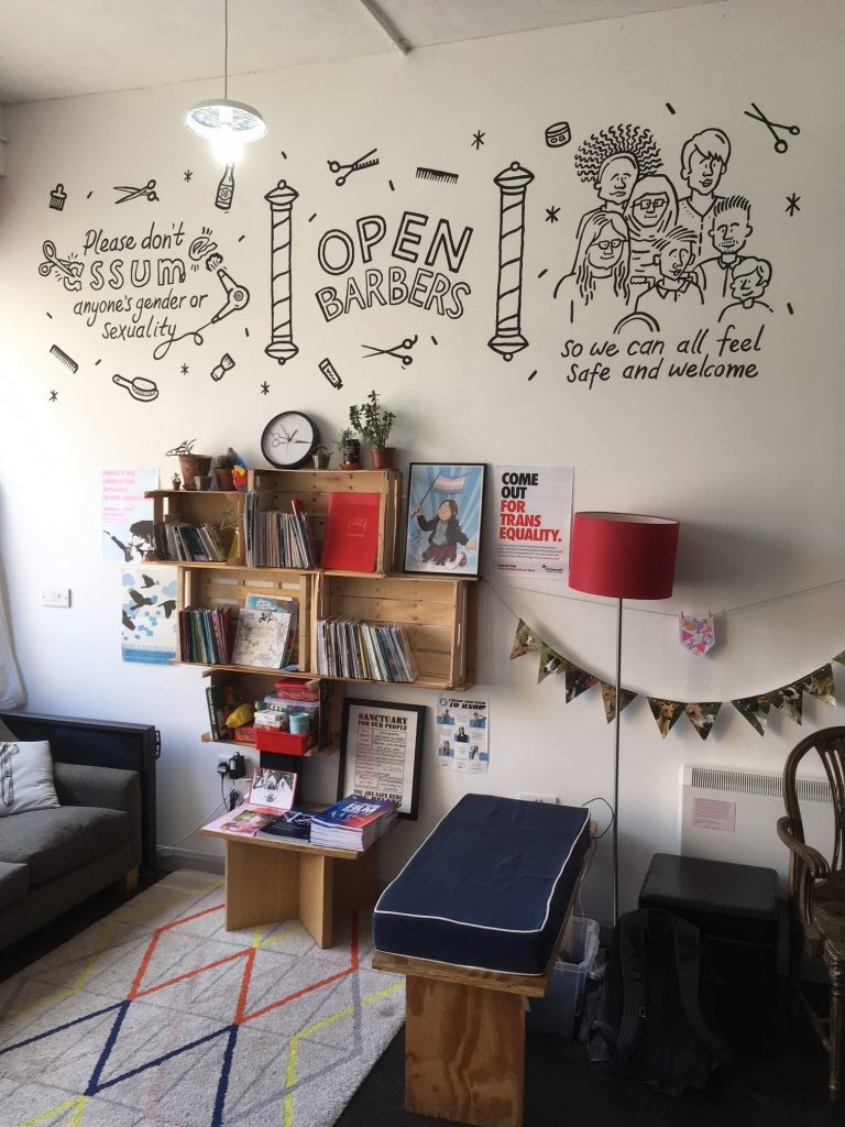 The inside of the Open Barbers salon, featuring the zine library and seating