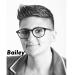 A black and white photo of Bailey with short hair, dark glasses and softly smiling to the camera with their name Bailey at the left side