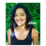 a photo of Jilna, a brown skinned person with black curly hair, wearing a black tank top and a dangly earring, smiling widely, with their name Jilna printed at the right side. They are standing in front of a background of green leaves.