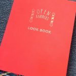 An image of Open Barbers Look book, bound in red with the salon's logo in gold print.